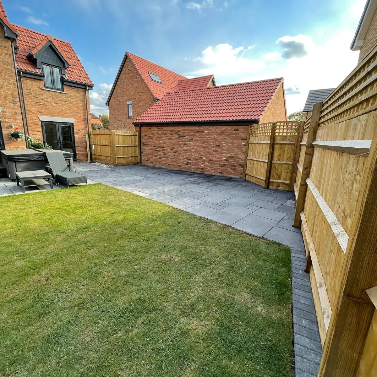 Completed back garden with new lawn, grey paving and timber fencing