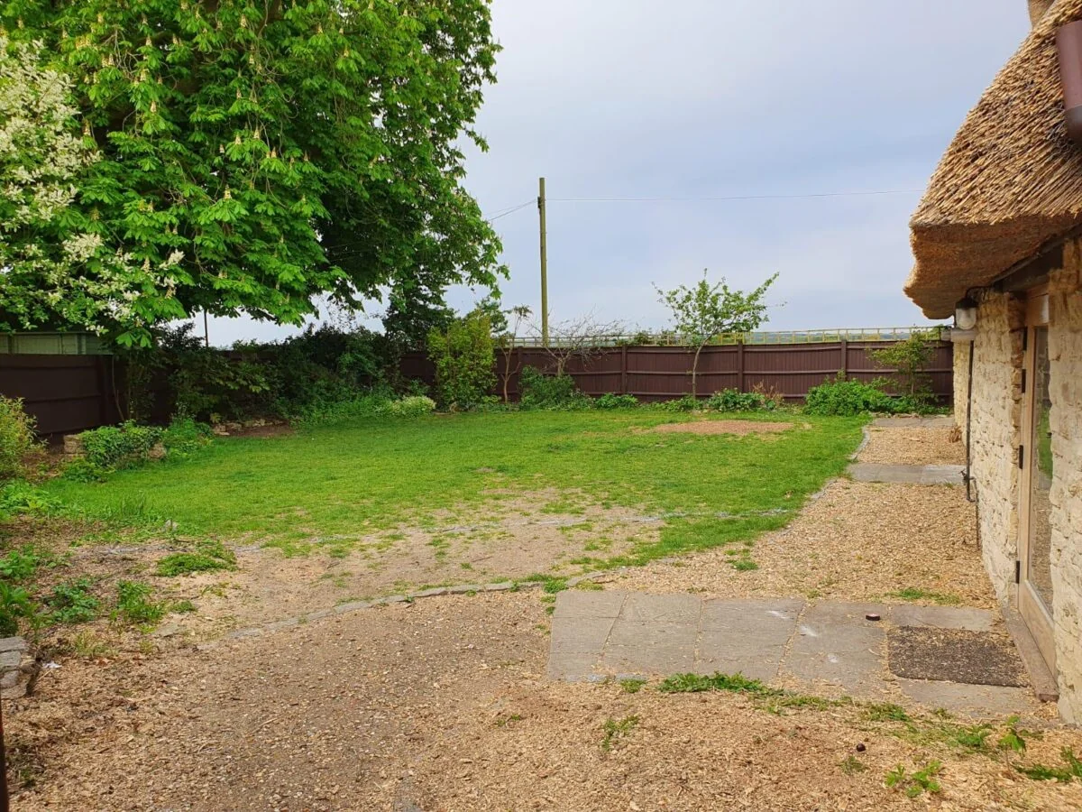Before: WV Landscapes completed sandstone patio and striped lawn beside a thatched cottage